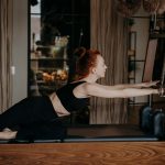Fit young pilates instructor stretching arms on cadillac reformer